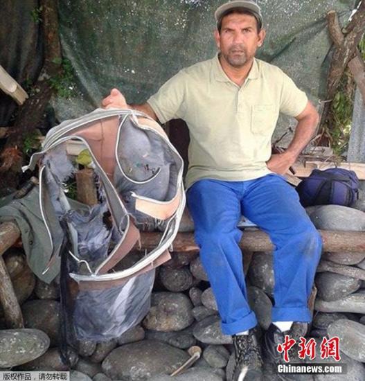 圖為當(dāng)?shù)貢r間7月30日，留尼旺島上的一名海岸清潔人員展示他找到的一個手提箱的殘骸。